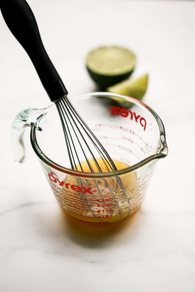 Whisking honey lime dressing in a measuring cup