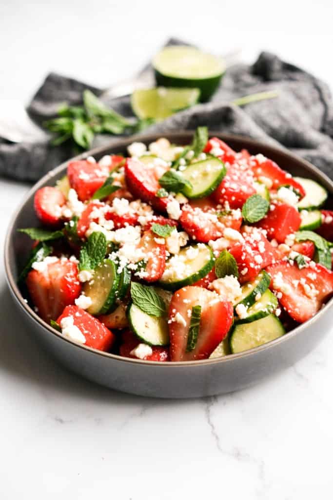A bowl with a combination of watermelon, strawberries, feta, cucumber and mint leaves.