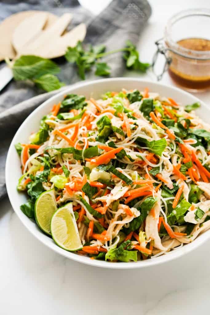 A bowl of Vietnamese Noodle Salad with dressing in the background