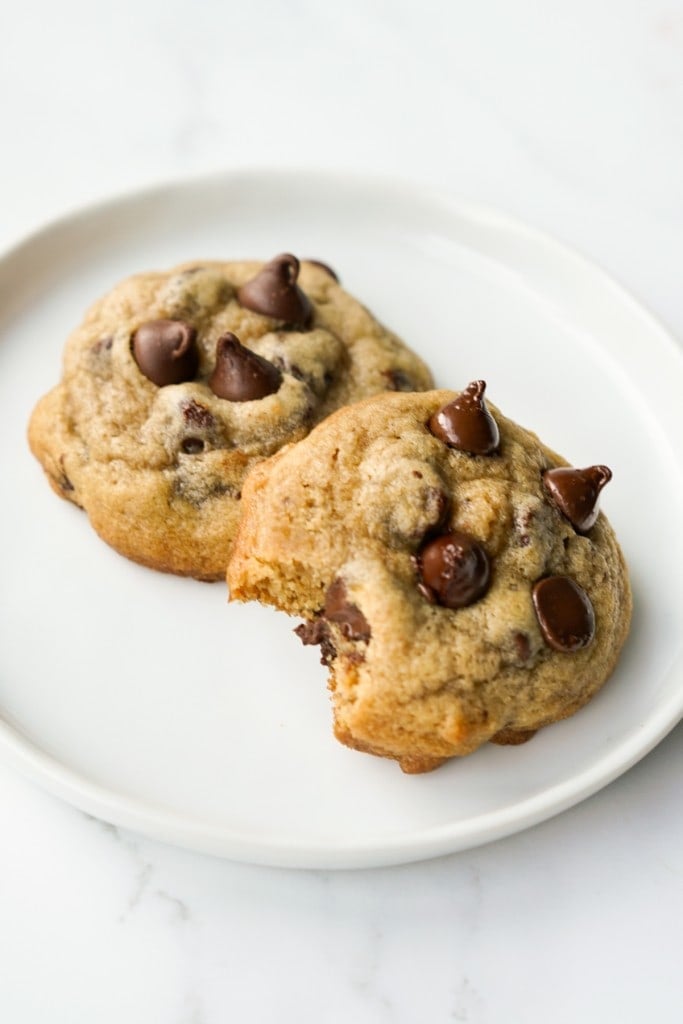 A bitten chocolate chip cookie and a whole one on a small plate