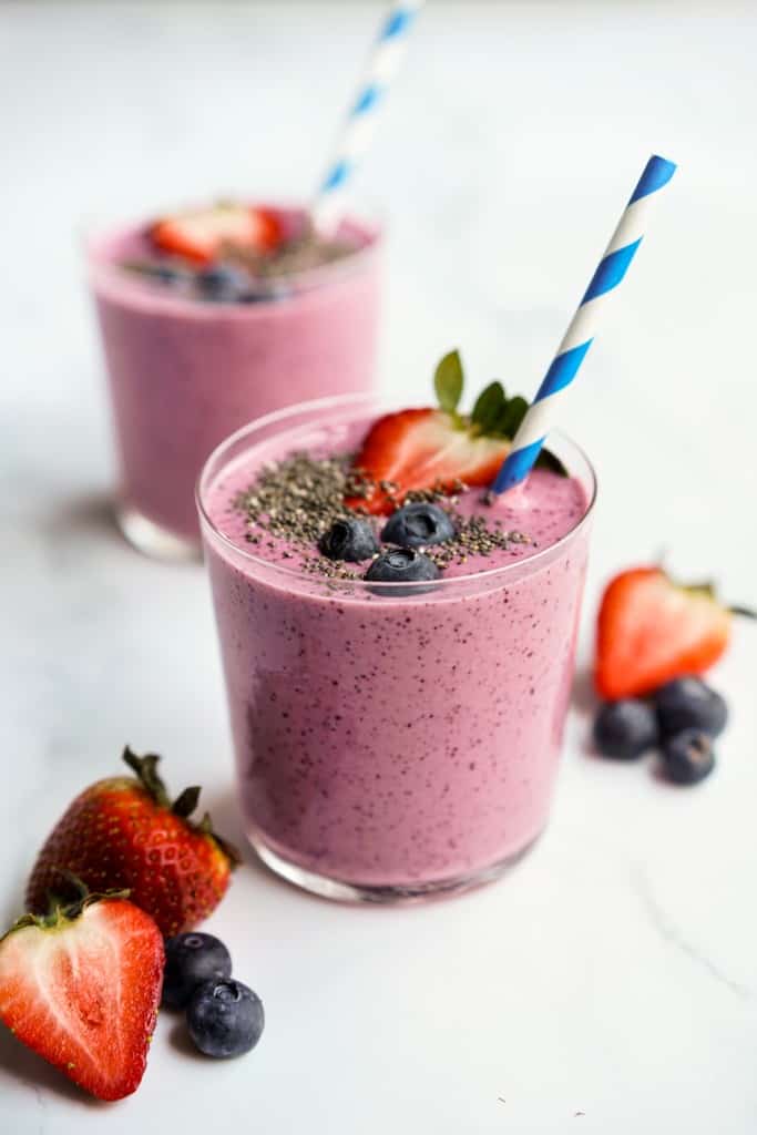 Two glasses of strawberry banana blueberry smoothie.