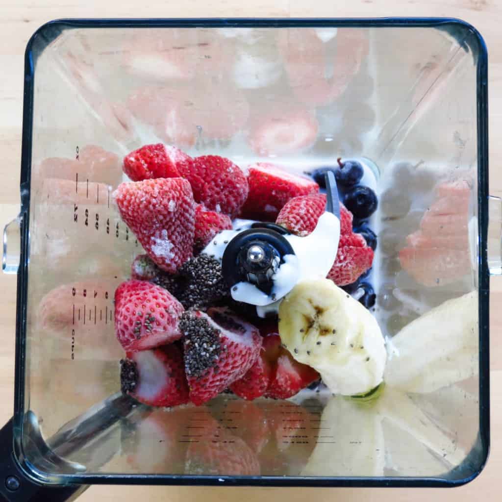 Frozen strawberries, blueberries, bananas, milk and yogurt in a blender