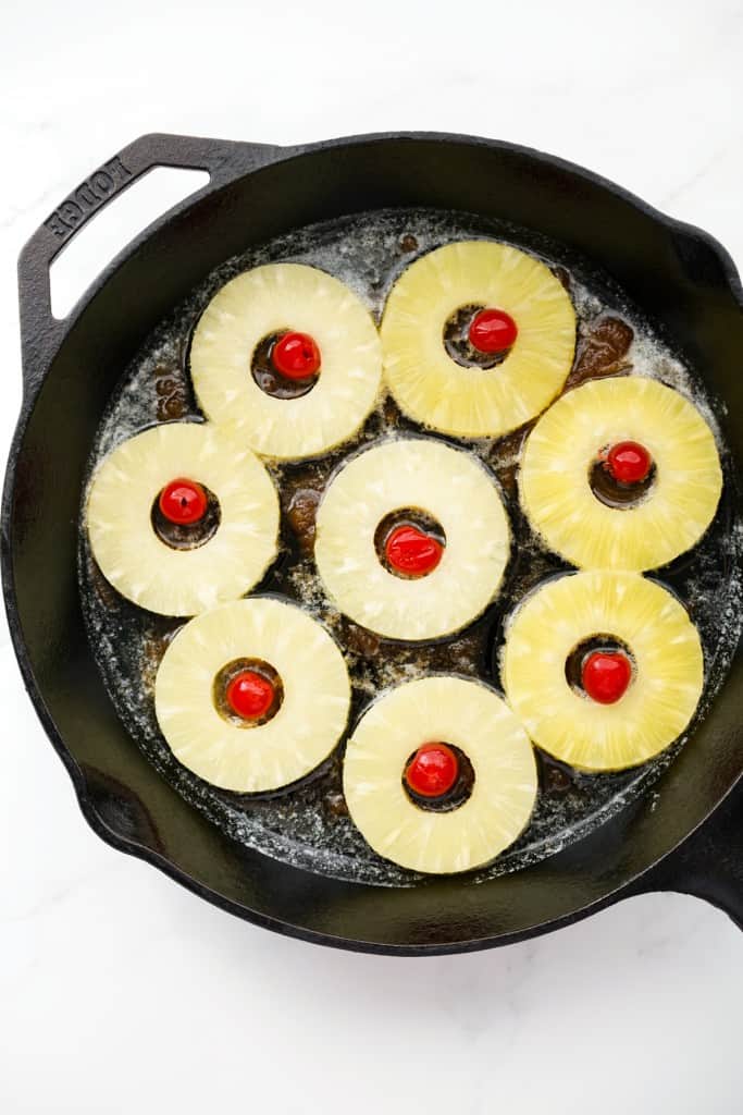 Pineapple rings and maraschino cherries on a cast iron skillet