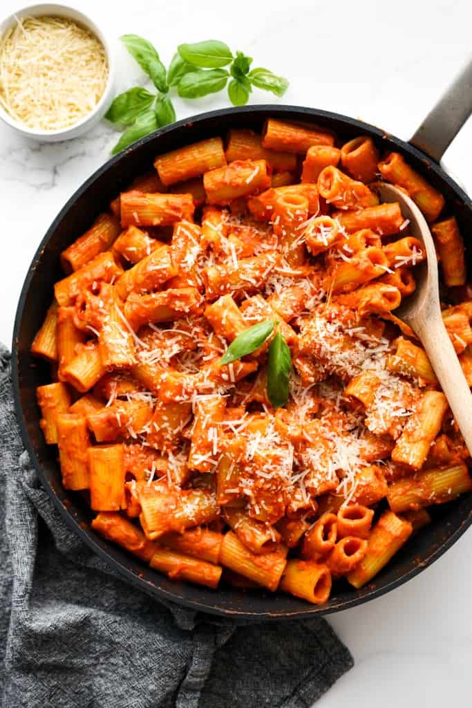 Top down view of a  nonstick skillet filled with the brim with spicy rigatoni in thick tomato sauce, topped with parmesan cheese
