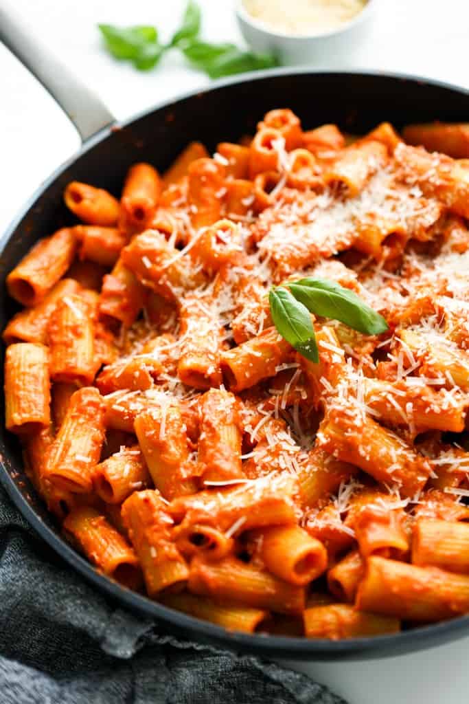 A skillet of spicy rigatoni topped with parmesan and basil