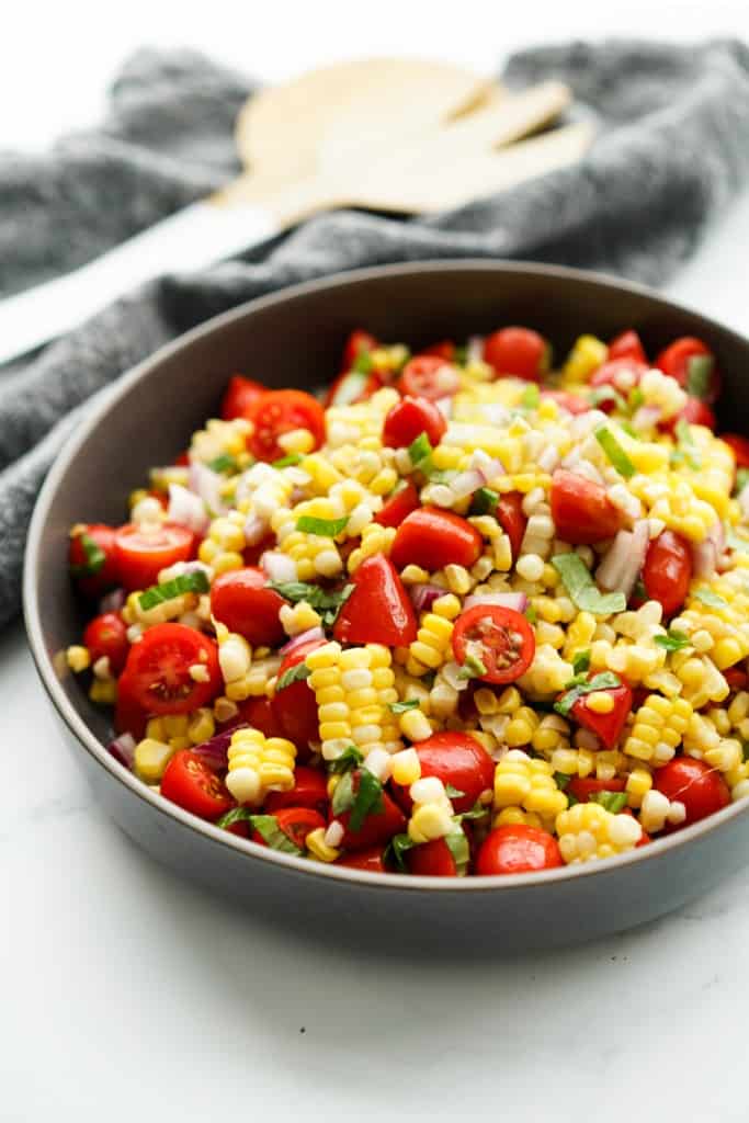 A bowl of Fresh Corn Tomato Salad tossed with fresh basil and red onions