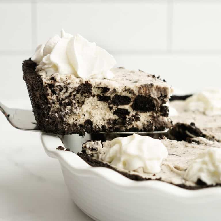 Lifting out a slice of Oreo Cream Pie from a white pie dish
