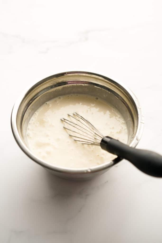Creamy dressing in a small mixing bowl, with a whisk in it