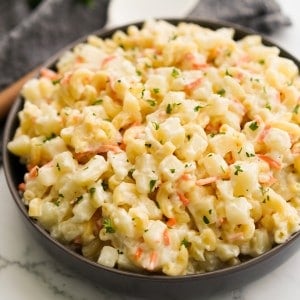 A bowl of macaroni past and diced potatoes tossed in a creamy dressing