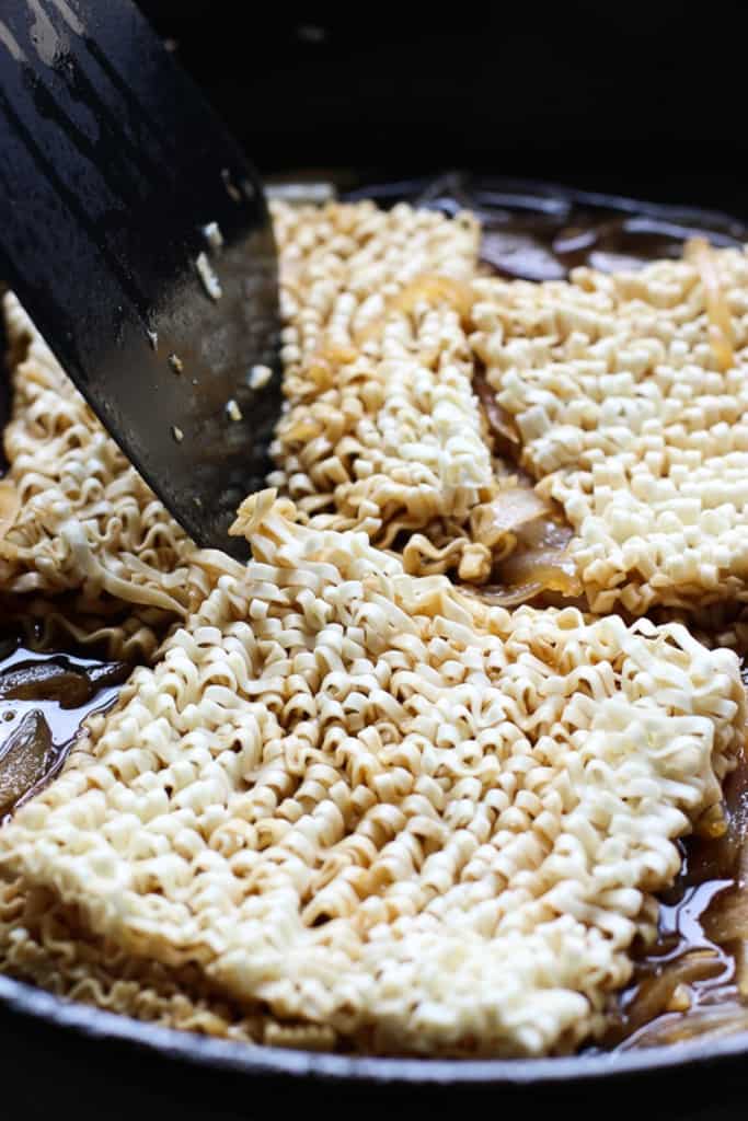 Submerging ramen noodles in sauce using a spatula