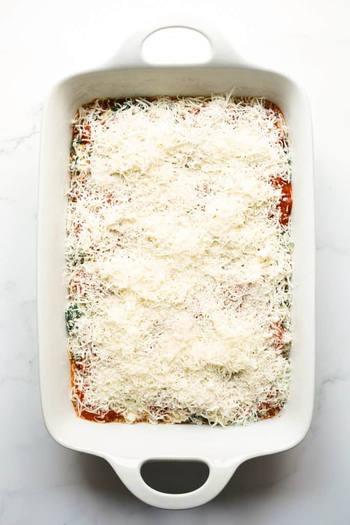 Unbaked spinach lasagna topped with mozzarella cheese on top