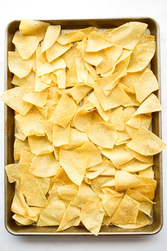 Tortilla chips spread out on a sheet pan