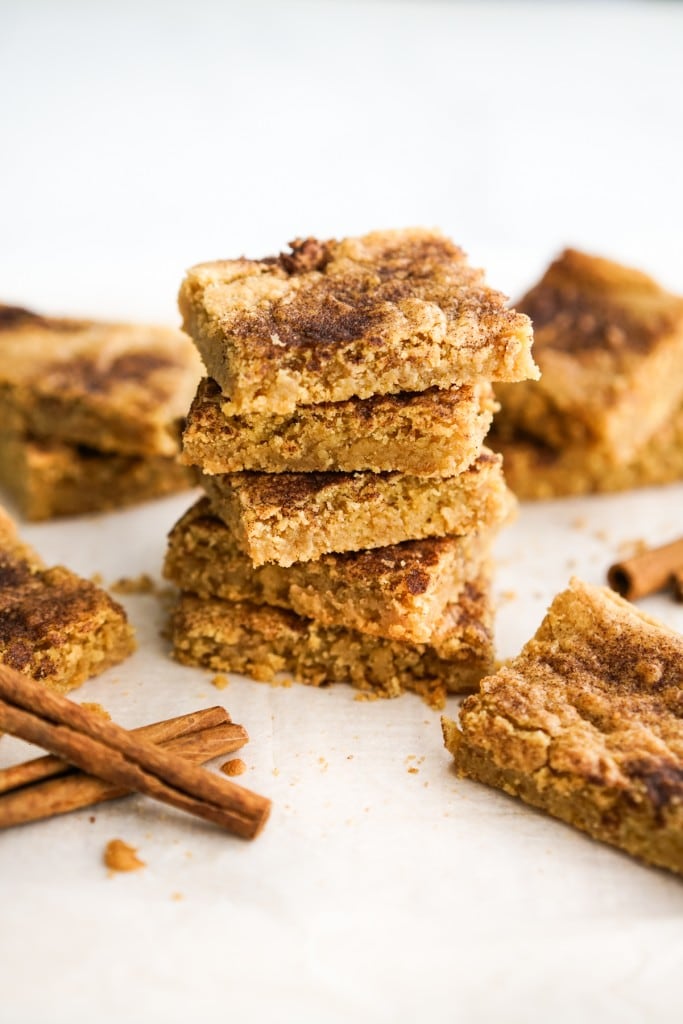 A stack of snickerdoodle bars with cinnamon sticks on the side