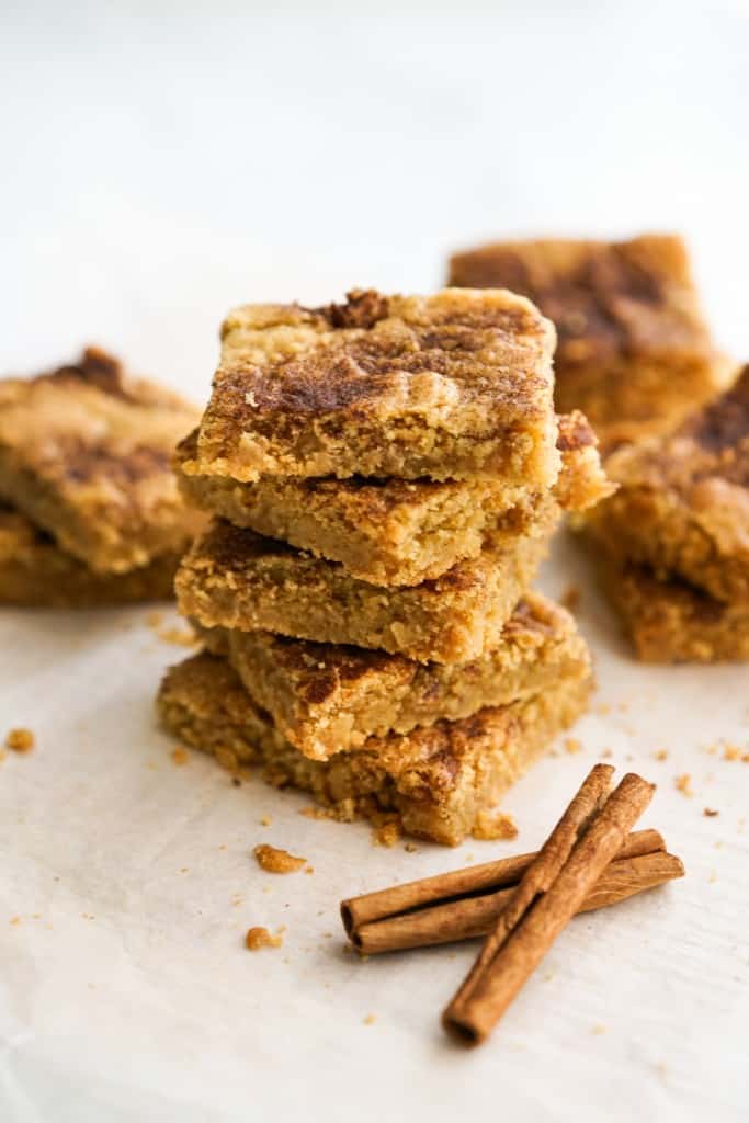 Stacking snickerdoodle square cookie bars on top of each other.