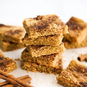 a stack of square cookie bars with cinnamon dusting on top