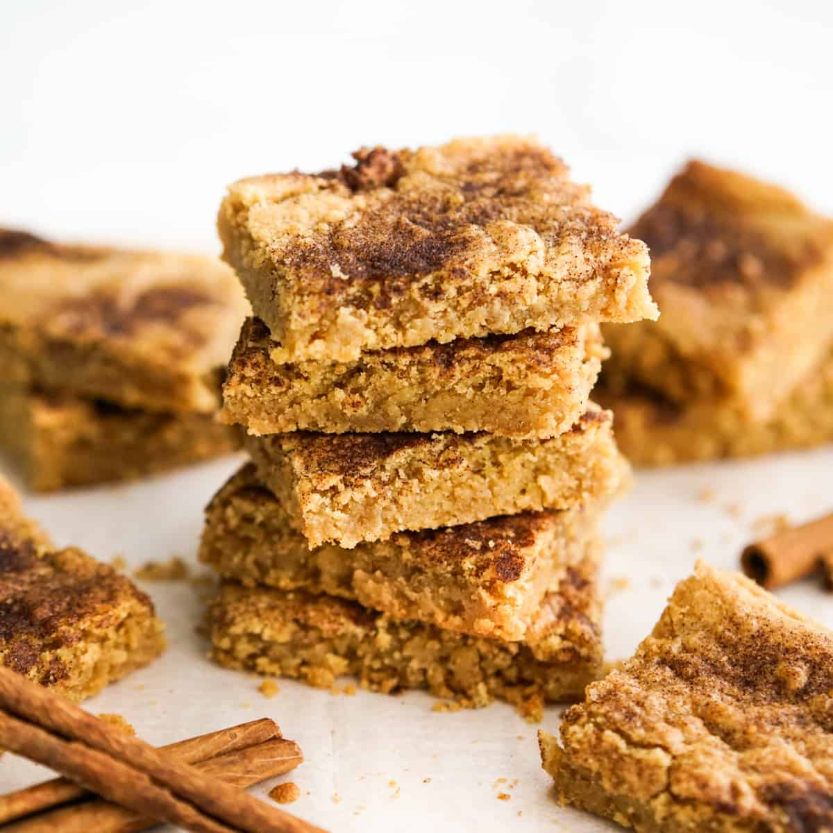 a stack of square cookie bars with cinnamon dusting on top