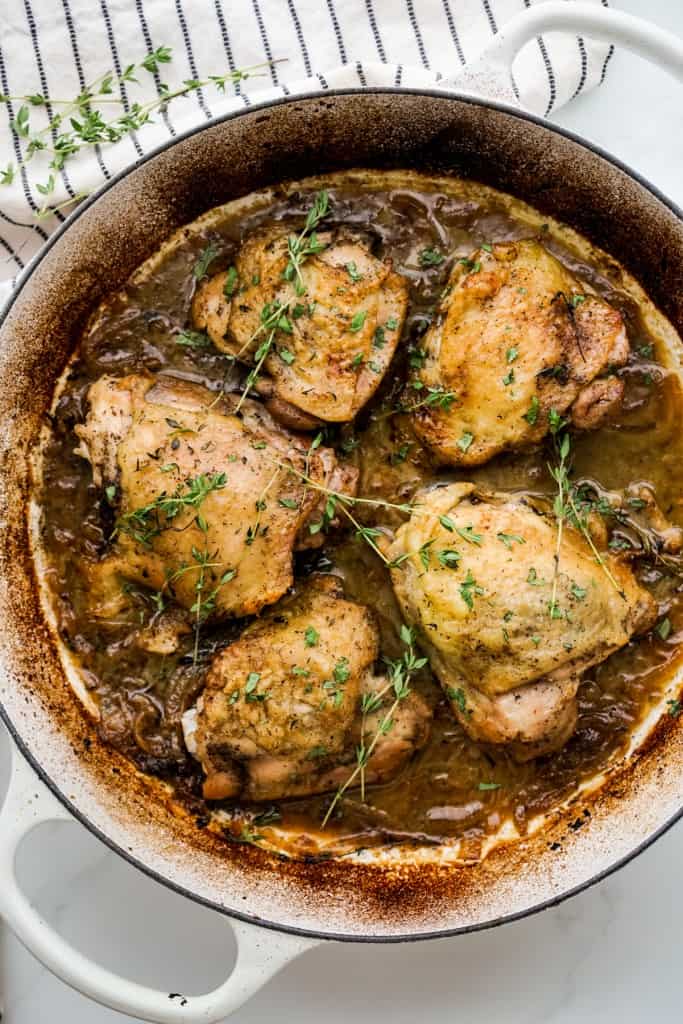 Chicken thighs braised in a brasier with brown sauces and  topped with herbs