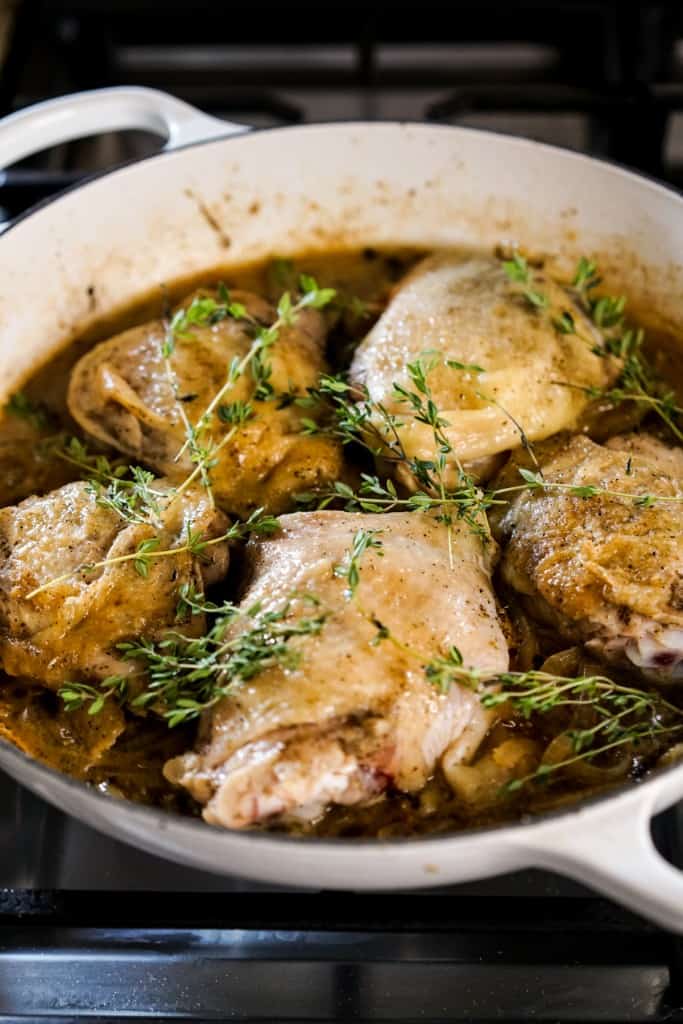 Chicken thighs topped with fresh herbs prior to baking