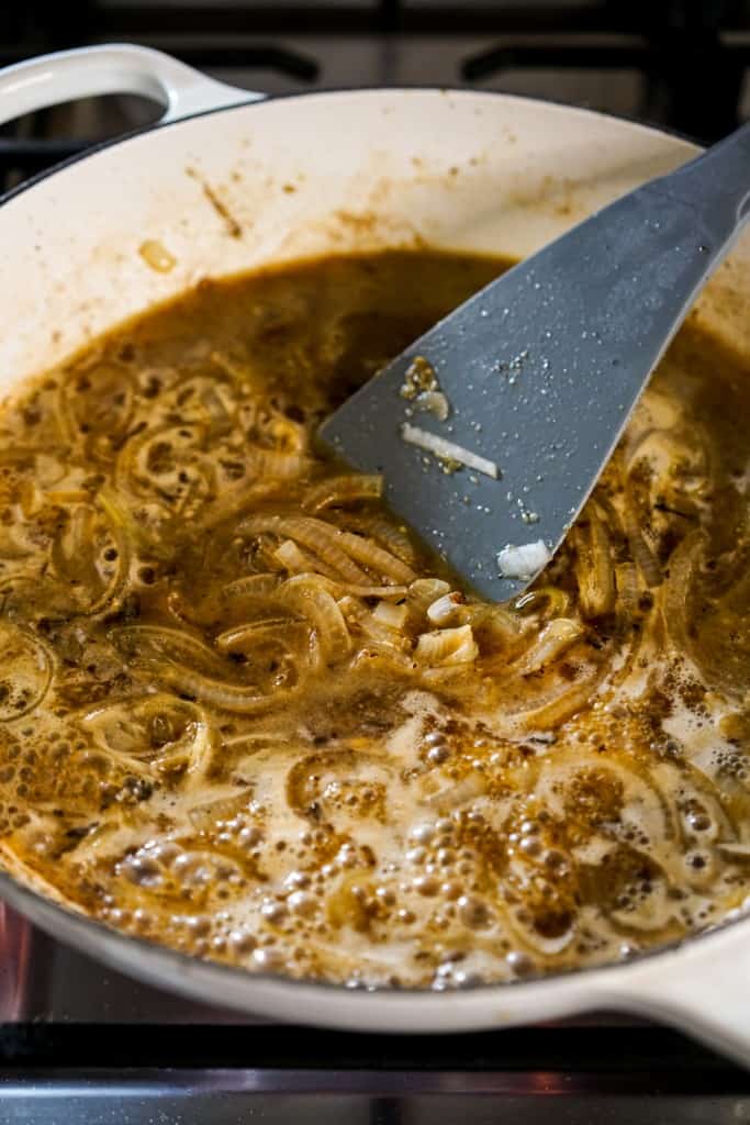 Deglazing the braiser by adding broth and wine to it