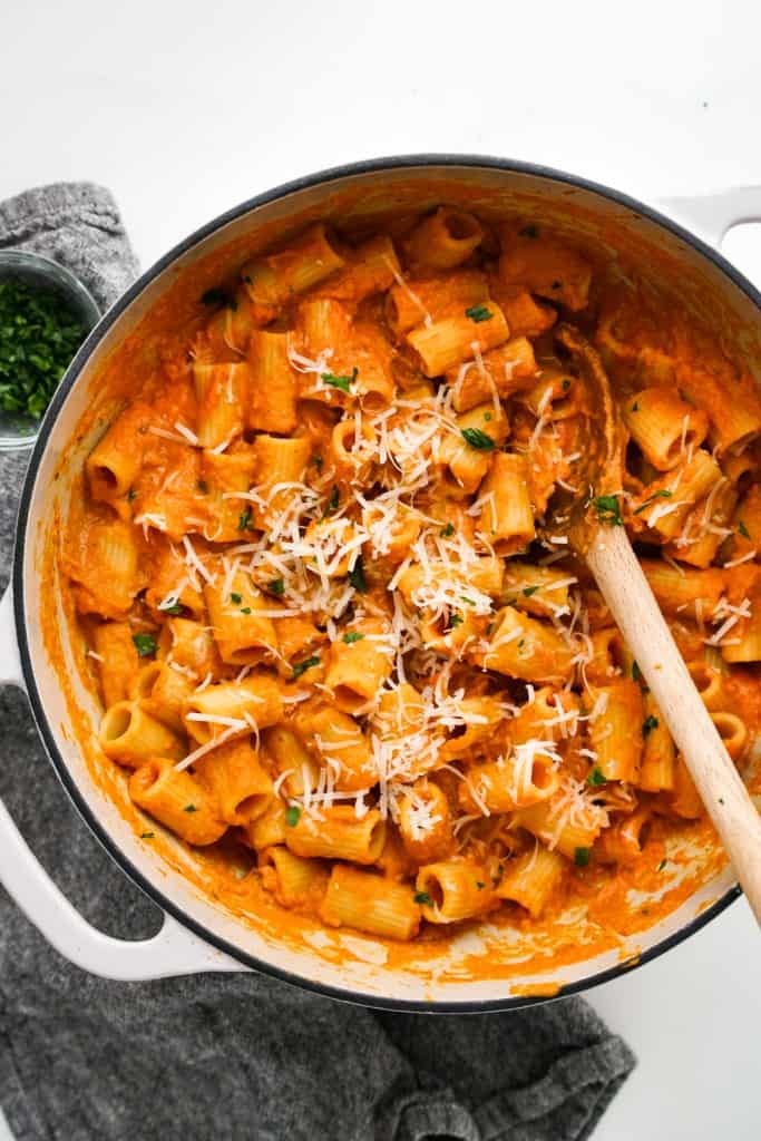 A large pot of creamy pumpkin pasta topped with parmesan cheese