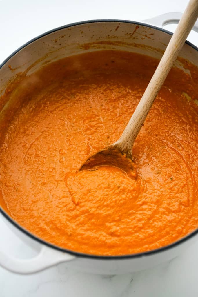 Creamy and smooth pumpkin sauce in a pot with a wooden spoon