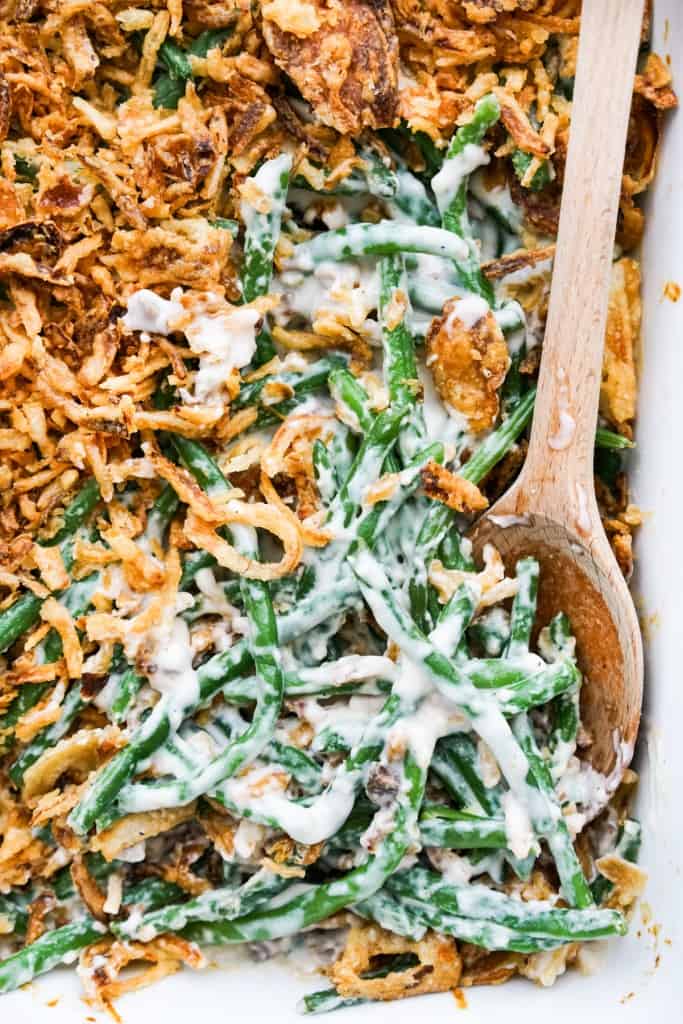 A wooden spatula digging into fresh green bean casserole 