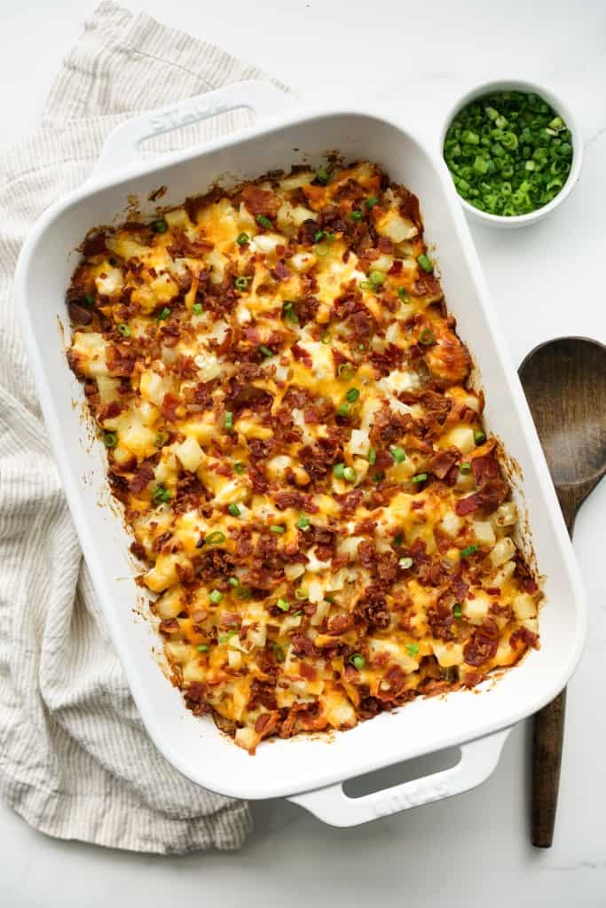 Top down view of a large casserole dish of potatoes with bacon and cheddar