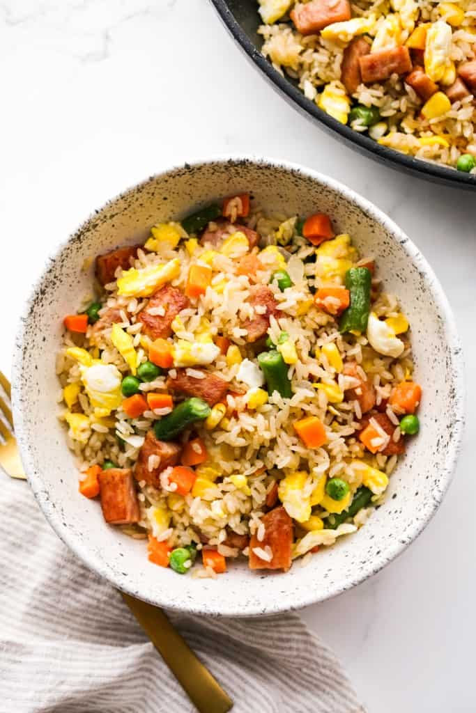 Top down view of a bowl of fried rice with spam and veggies.