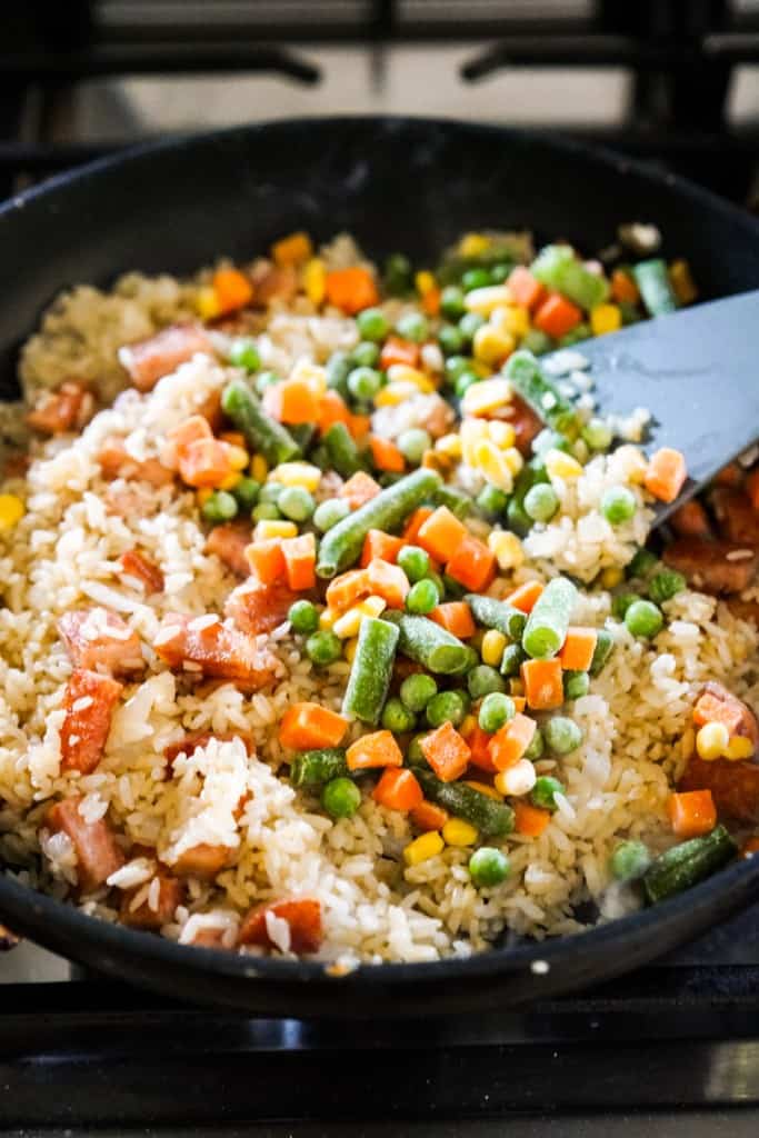Adding frozen mixed vegetables to fried rice