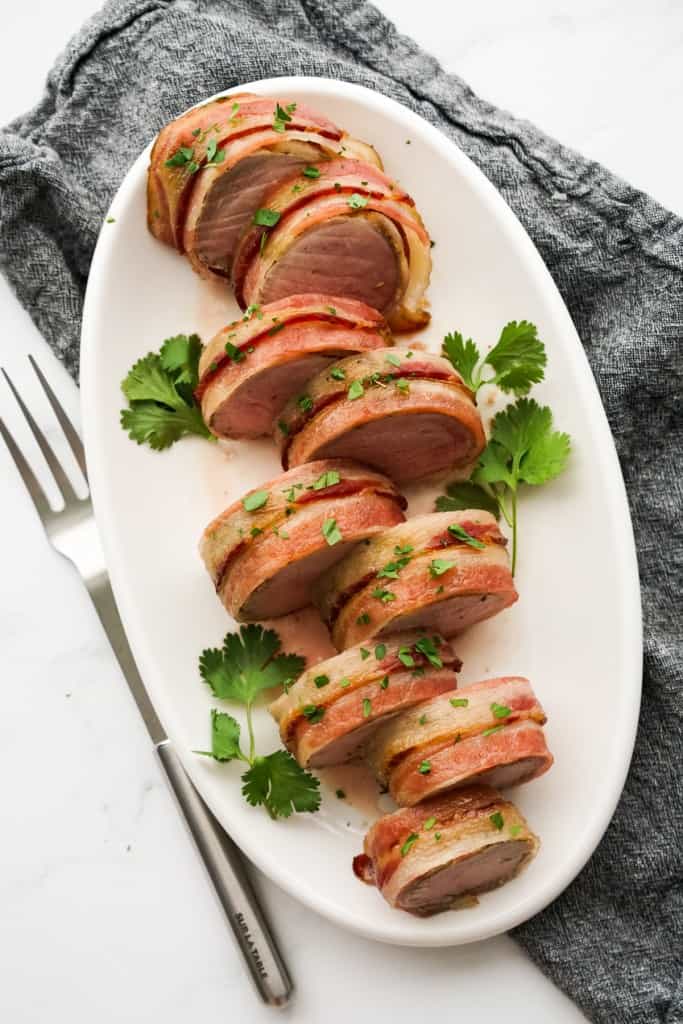 Top down view of bacon wrapped pork tenderloin sliced into smaller pieces