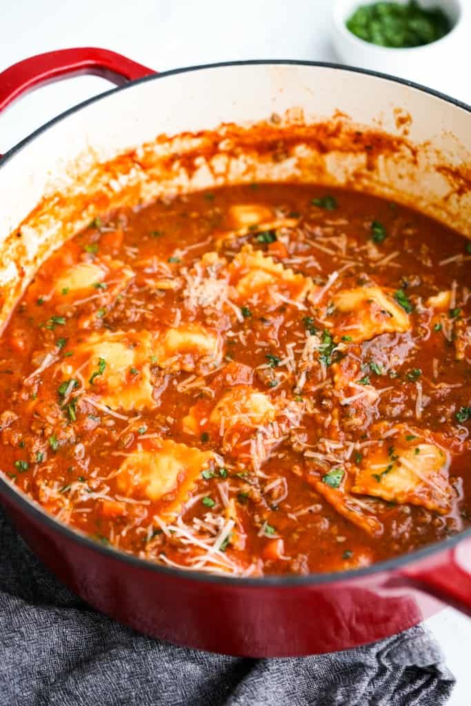 A large pot of thick chunky soup loaded with raviolis, ground beef, tomatoes and carrots