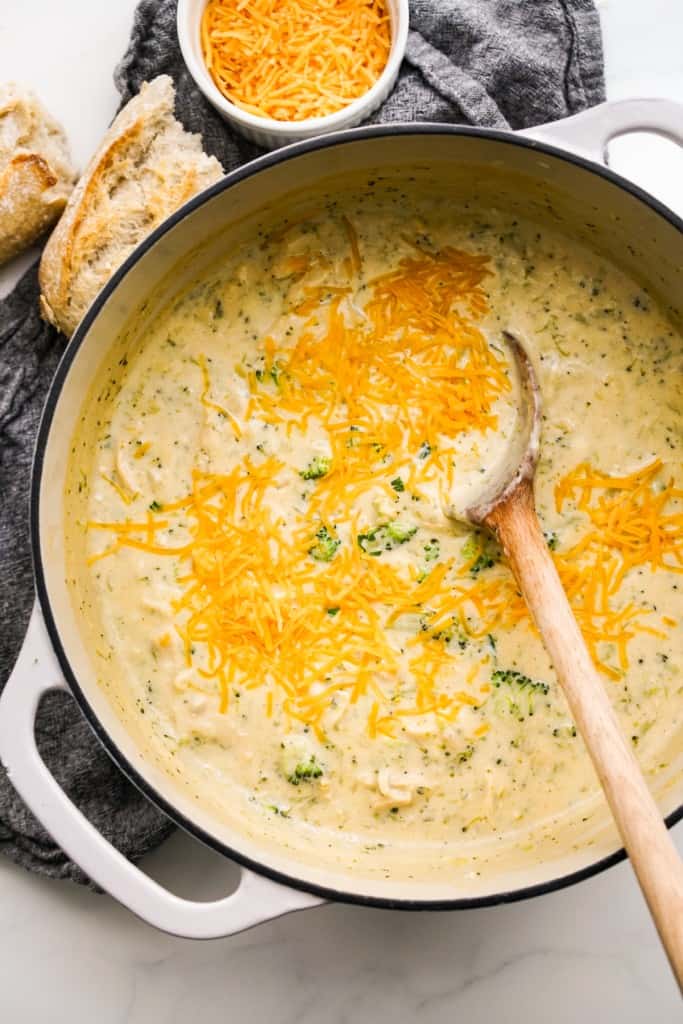 A large pot of chicken broccoli cheese soup topped with shredded cheddar