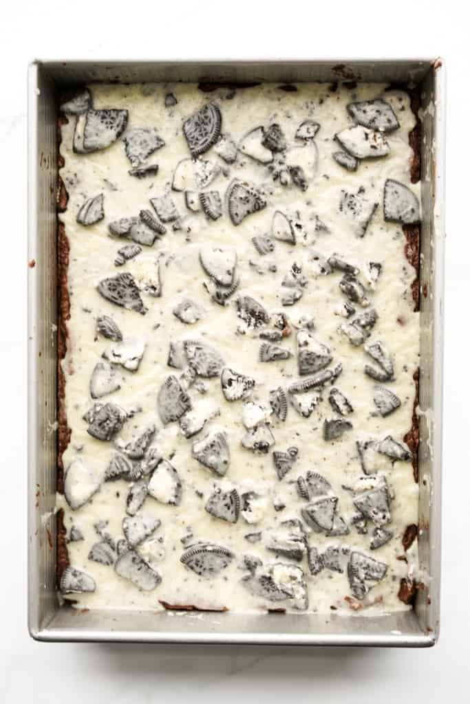 Brownie batter topped with Oreo icing in a rectangular metal baking dish
