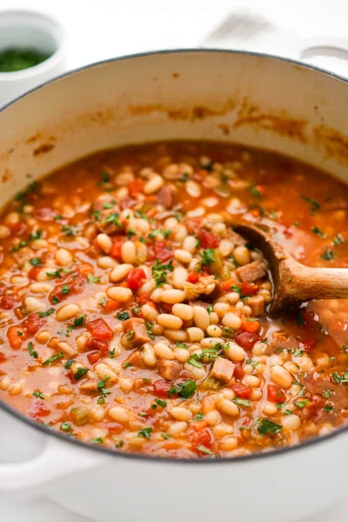 Stirring a pot of Navy Bean and Ham Soup with a wooden spoon