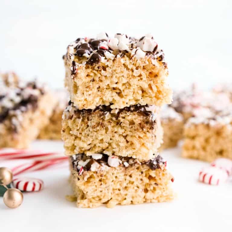 A stack of peppermint rice krispie treats with Christmas holiday decor in the background