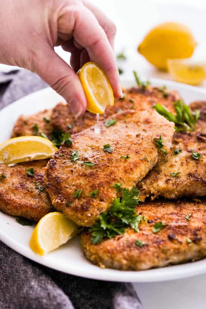 Sprinkling lemon juice onto parmesan crusted pork chops