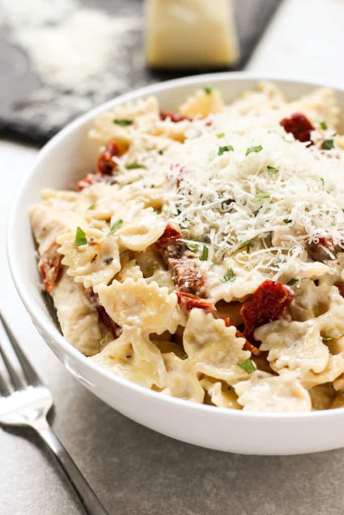 A bowl of creamy sundried tomato pasta with chicken topped with parmesan