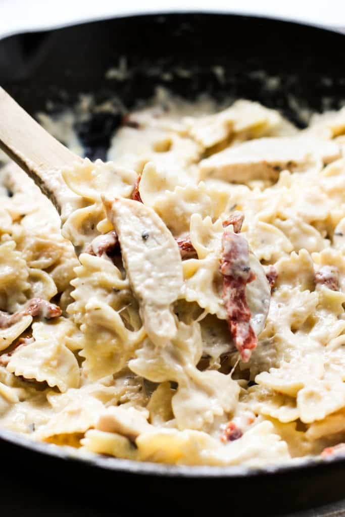 Stirring creamy pasta with wooden spoon