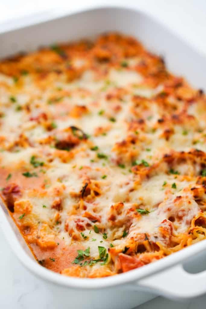 Baked chicken spaghetti in a casserole dish topped with melted cheese