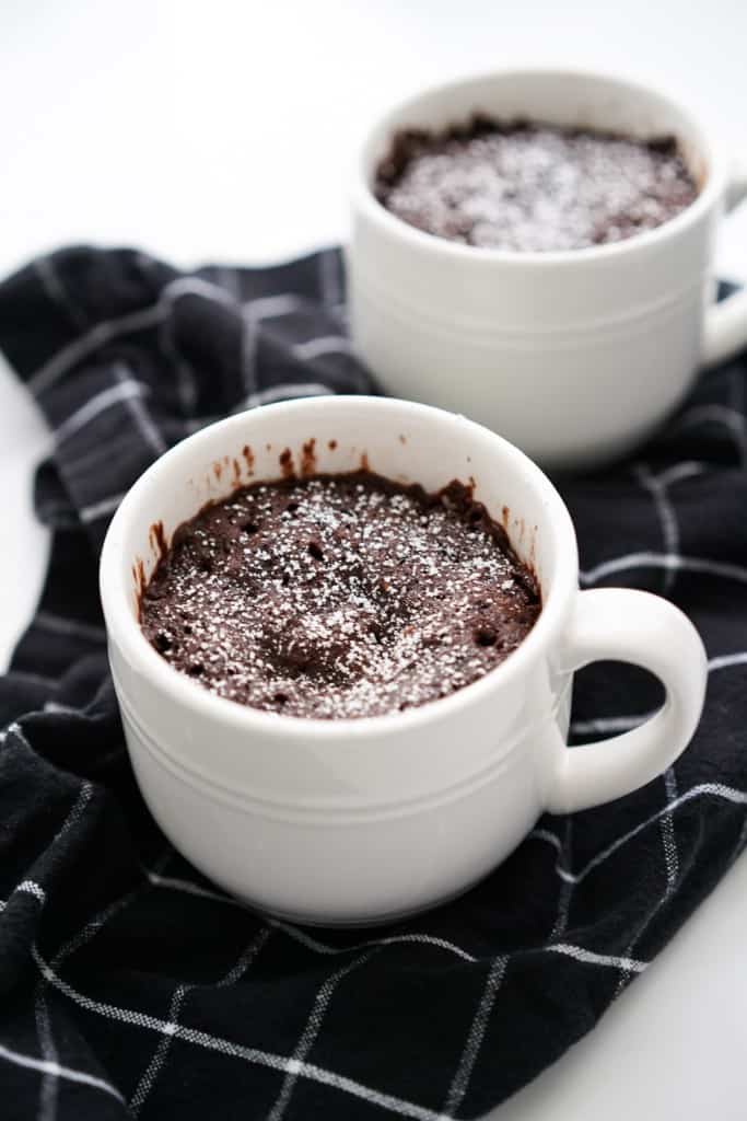 Two chocolate mug cake topped with powdered sugar