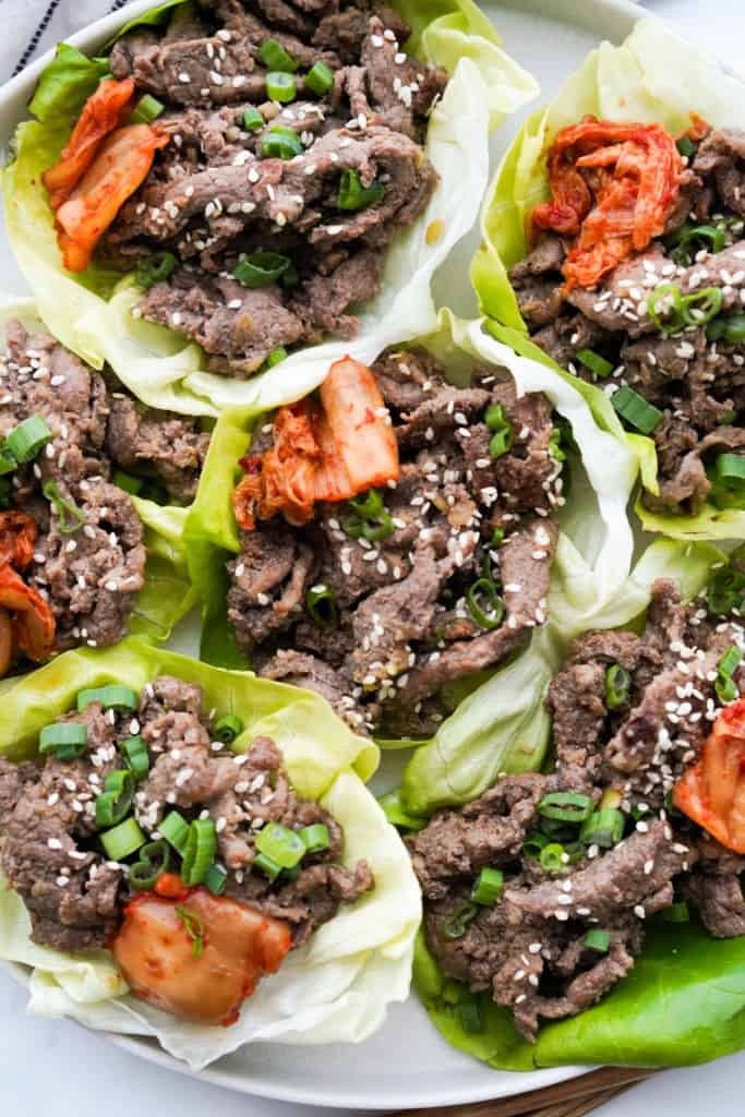 Close up on 6 lettuce bibb filled with bulgogi beef and kimchi