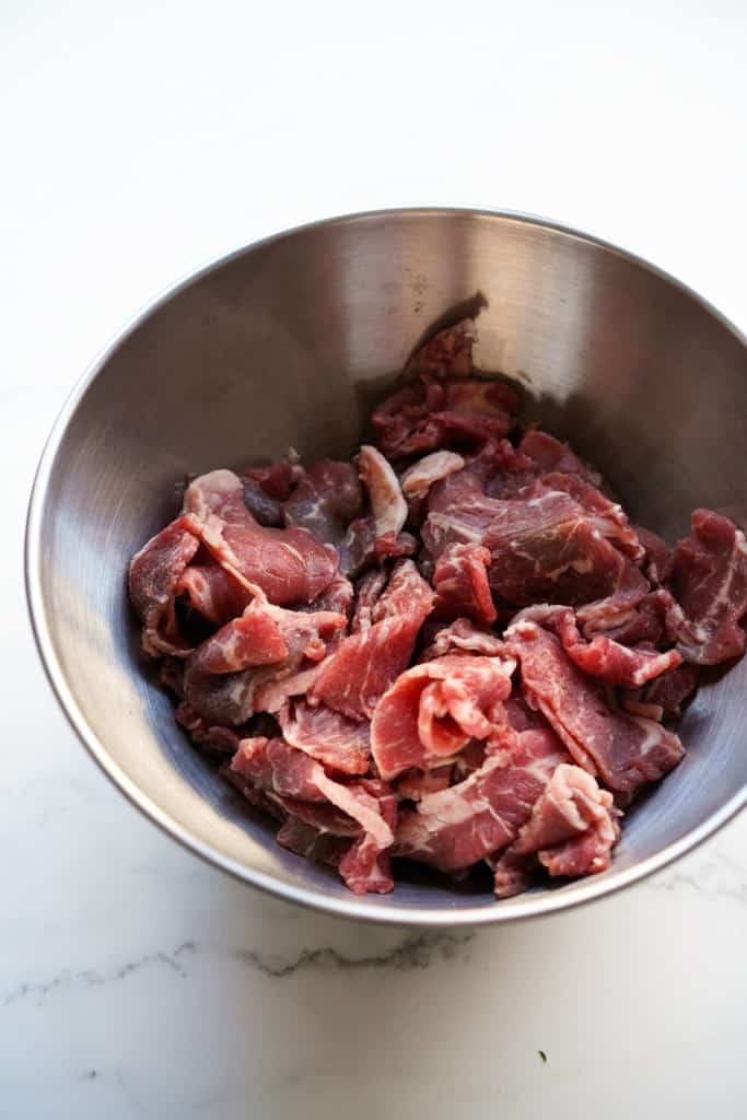 Thinly sliced beef in a large mixing bowl