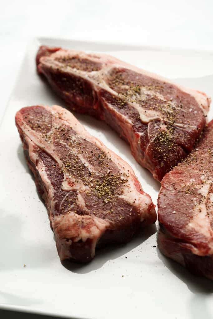 Raw lamb chops generously seasoned with salt and black pepper