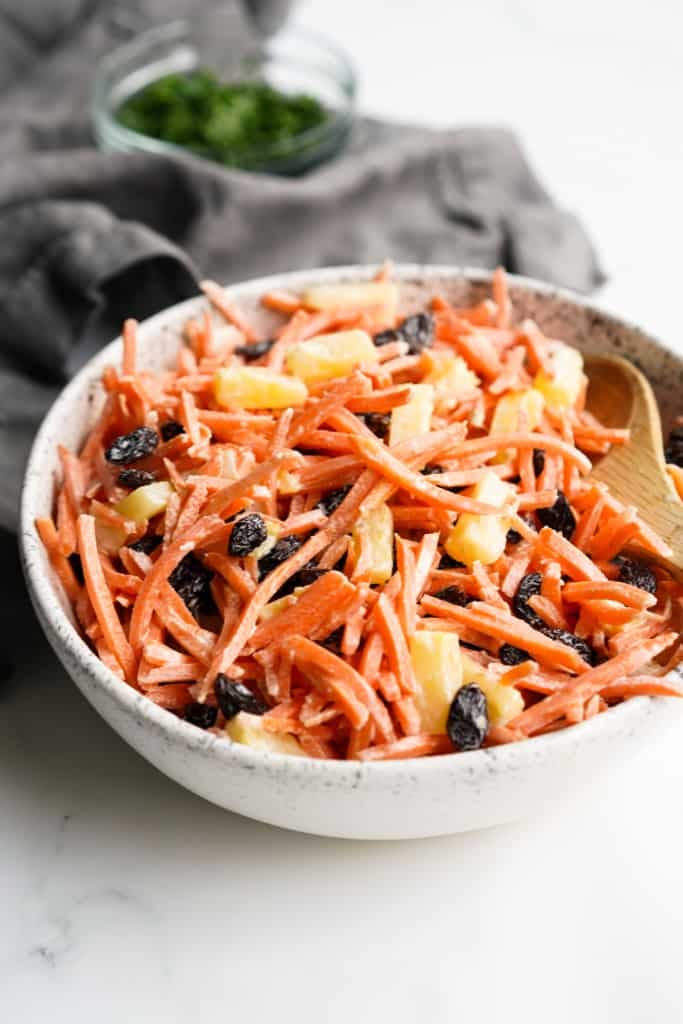 A bowl of carrots with raisins and pineapple
