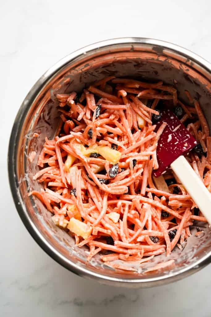 Carrot raisin pineapple salad mixed together in a large mixing bowl