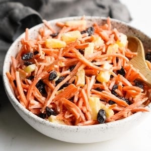 A bowl of shredded carrot raisin salad with pineapple pieces