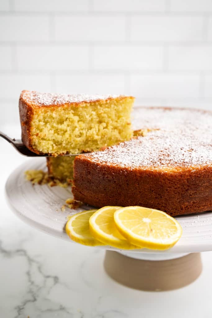 Picking up a slice of olive oil cake from the cake stand