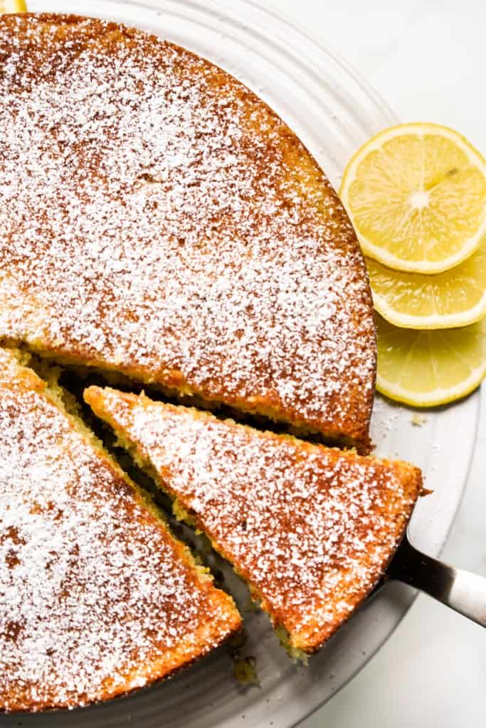 Cutting out a slice of lemon olive oil cake using a cake cutter