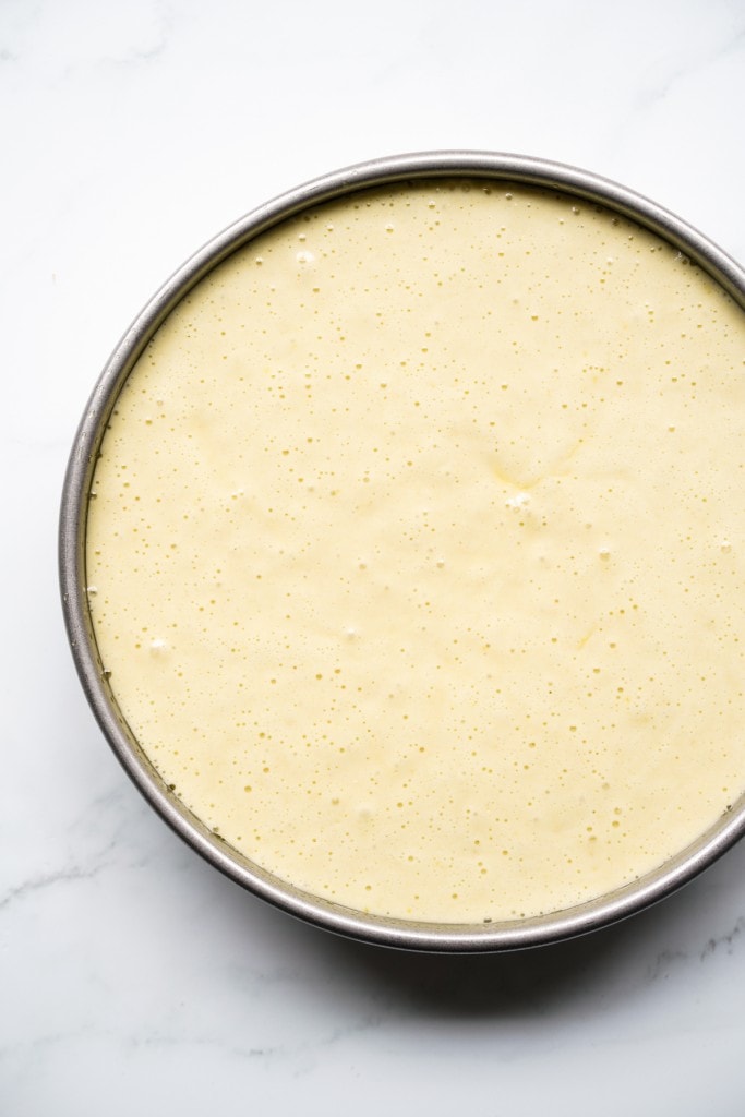 Unbaked lemon olive oil cake batter in a round cake pan.