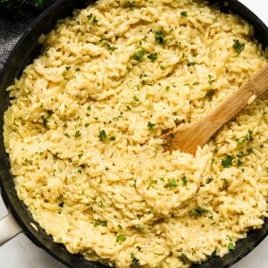 A skillet filled with creamy parmesan orzo topped with parsley